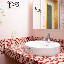 ピンクのタイルと花柄のクロスを組み合わせかわいらしい雰囲気いっぱいの洗面室